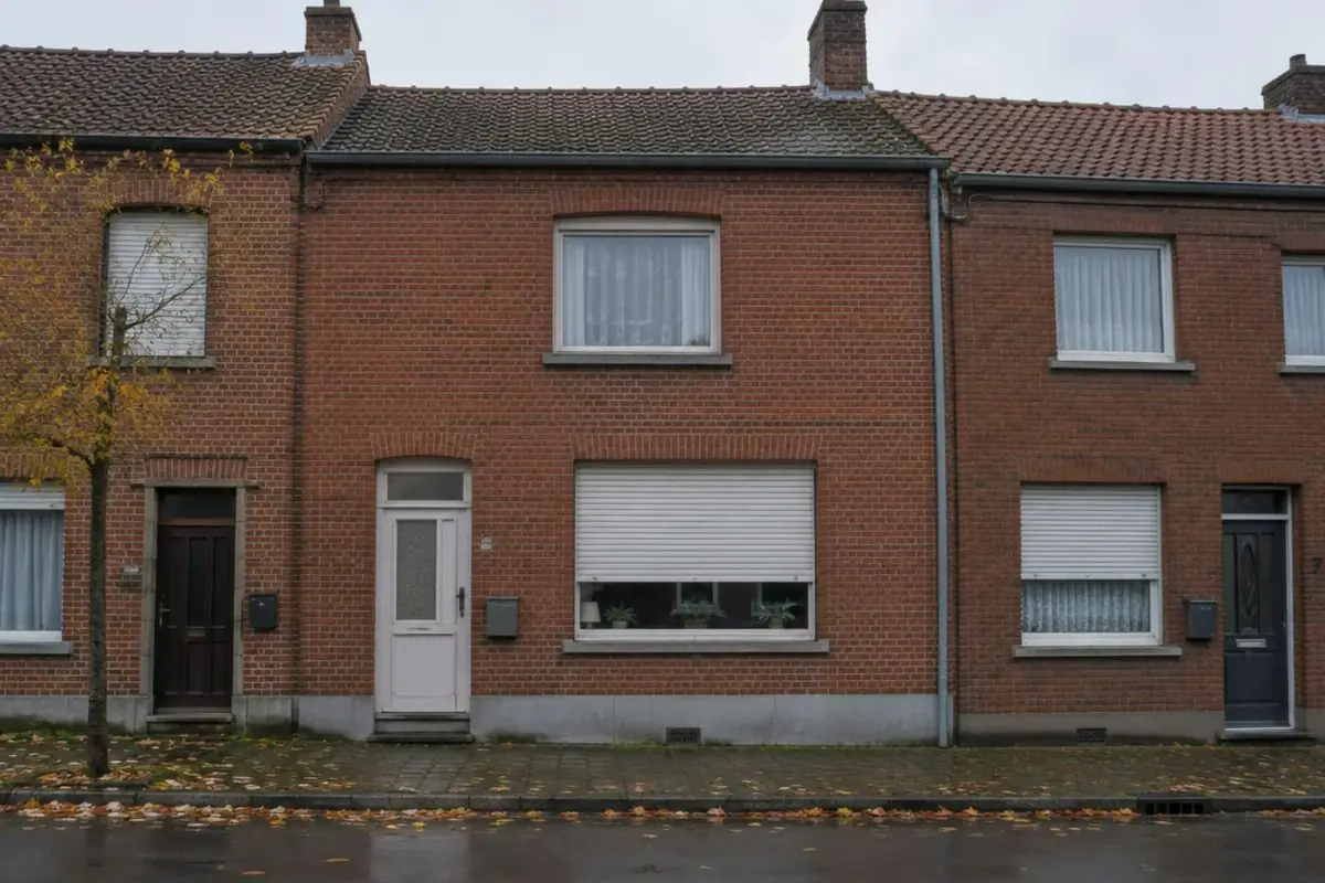 Maison ouvrière mitoyenne en brique à Tubize, volet roulant blanc bloqué à mi-hauteur